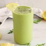 Showing is a tall glass of green arugula smoothie garnished with chia seeds.