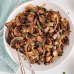 View on some caramelized mushrooms and onions in a bowl with a large spoon.