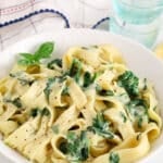 Front angle view on a bowl of vegan creamy spinach pasta made with lemon and basil.