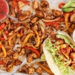 Overhead view on a sheet-pan tofu fajitas tray with vegan sour cream and salsa.