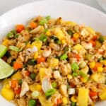 View on a pile of mango fried rice with vegetables topped with toasted cashews.