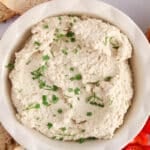 View on a bowl of vegan cream cheese made with sunflower seeds and garnished with chives and dill.