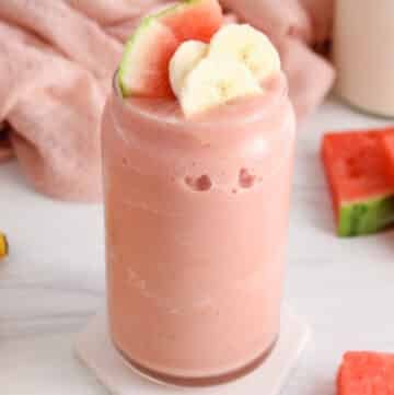 Showing a tall glass of frosty watermelon banana smoothie.