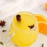 View on a mug filled with an orange peel tea garnished with a star anise and a cinnamon stick.