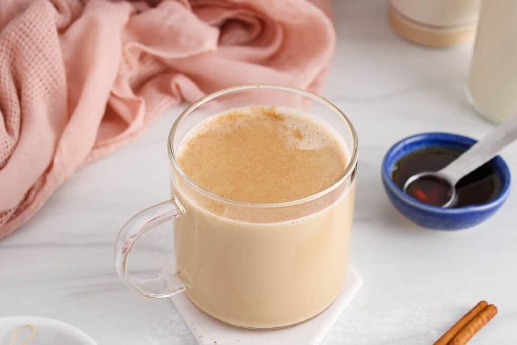 View on a cup of cinnamon milk tea with some maple syrup on the side.