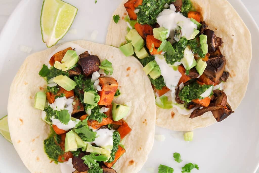 Close up on the filling ingredients of vegan sweet potato and mushroom tacos on a plate.