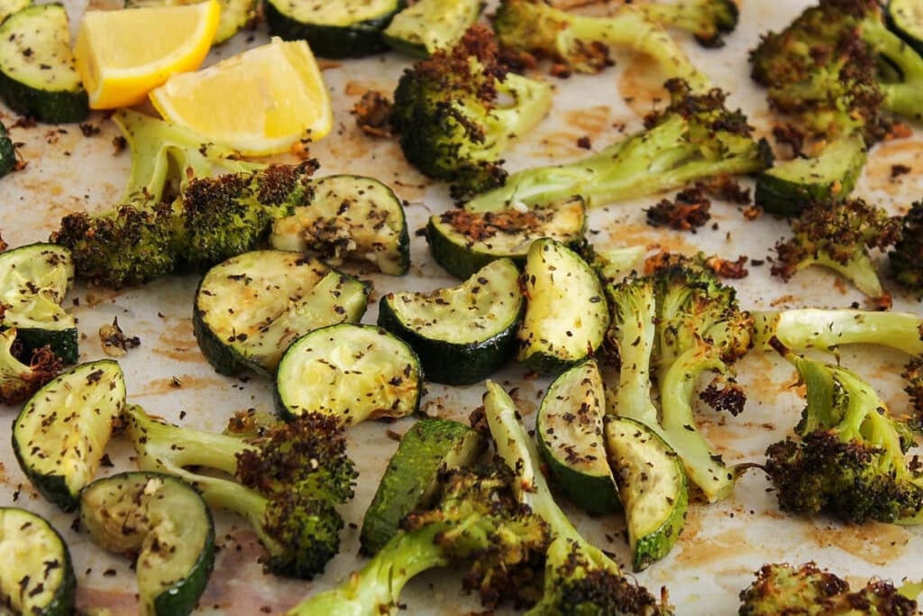 Front angle view on some roasted zucchini and broccoli tossed in herbs and lemon juice.