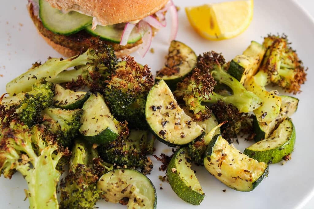 There are some roasted zucchini and broccoli on a small plate.