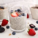 View on a small jar filled with an oat milk chia pudding garnished with berries.