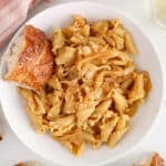 View on a bowl of vegan French onion soup pasta with a side of crusty bread.