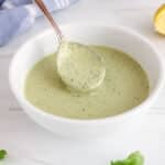 Close up on a spoon taking some lemon herb tahini dressing from a bowl to show the creamy texture.