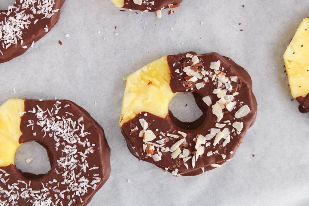 View on a slice of fresh pineapple covered with dark chocolate and garnished with almonds.
