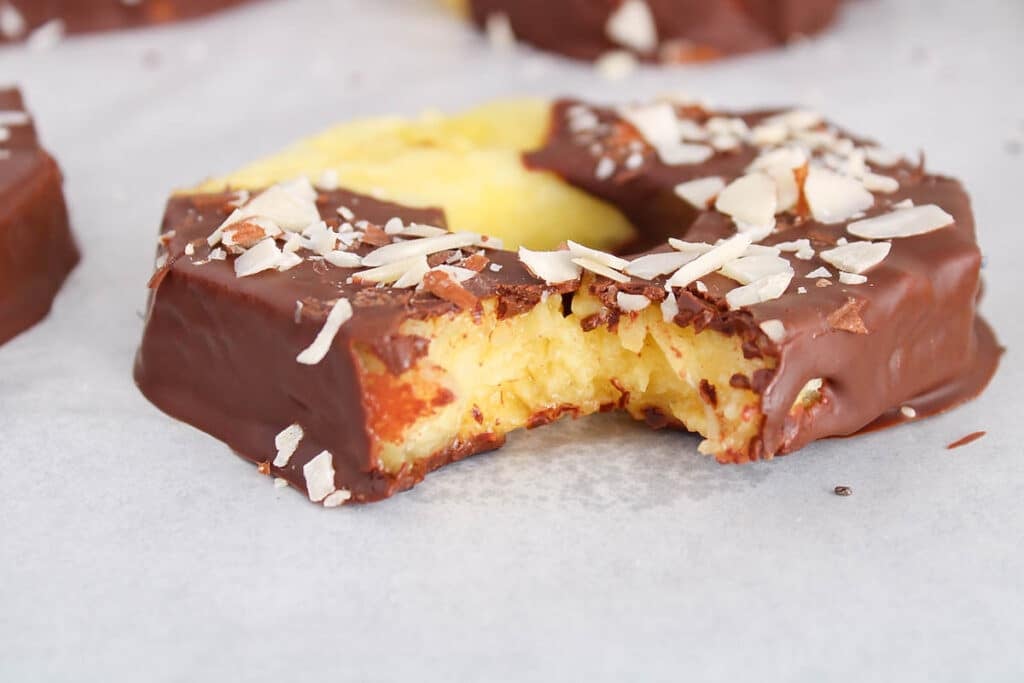 Close up on a chocolate covered pineapple with a bite taken off to show the middle part.