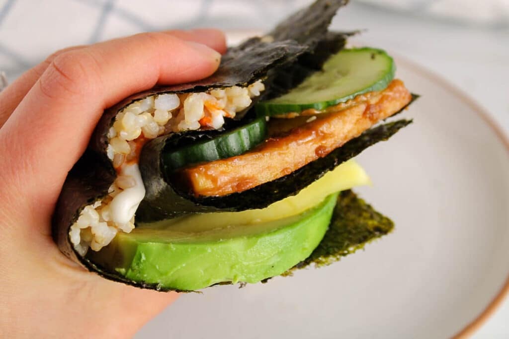 A hand holding a nori sushi wrap.