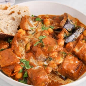 View on a bowl of vegan tikka masala made with eggplant ands chickpea with a side of bread.