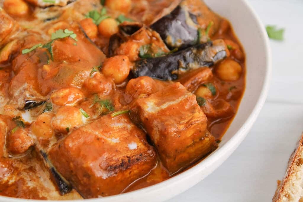 Close up on a large chunks of roasted eggplant in a creamy tikka masala sauce.