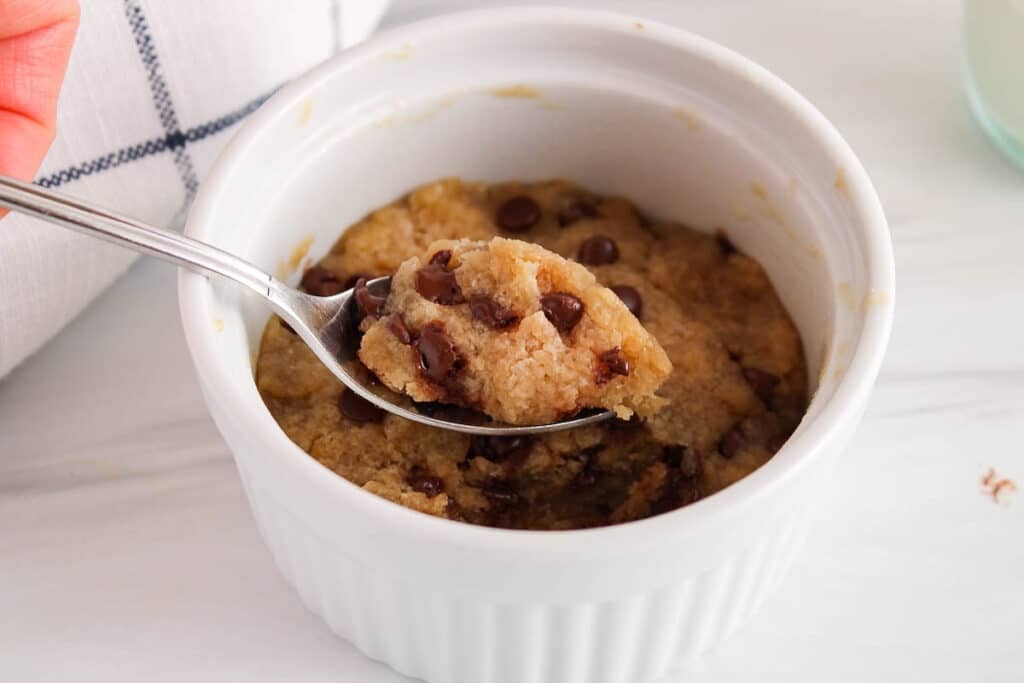 Close up on a spoon holding a bite of vegan chocolate chip cookie made in a mug using the microwave.