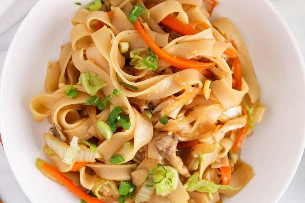 Close up on a bowl of Vietnamese stir-fried noodles with cabbage and carrot.