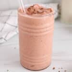 View on a tall glass of mango cherry smoothie topped with flaxseed.