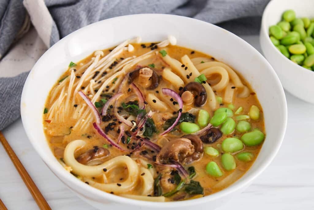 Showing a steamy bowl of healthy and vegan red curry udon noodles.