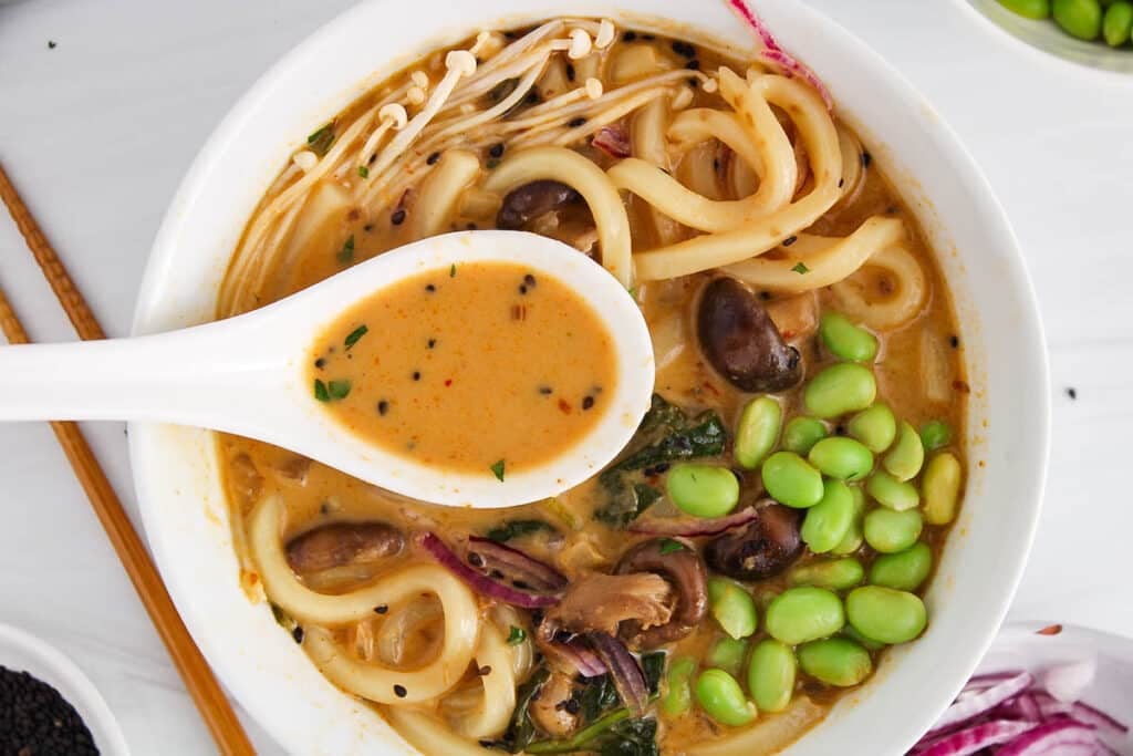 Overhead view on a Thai red curry coconut soup made with udon noodles and mushrooms.