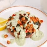 View on a vegan stuffed portobello mushroom on a plate that's drizzled with a tahini herb sauce.