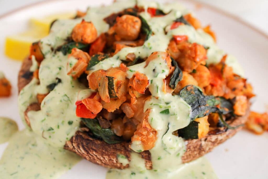 Close up on a vegan stuffed portobello mushroom with a tahini sauce drizzle.