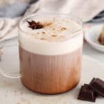 View on a mug of chocolate chai latte topped with oat milk foam and a star anise.