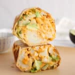 Showing 2 halved vegetarian buffalo cauliflower wrap over each other.