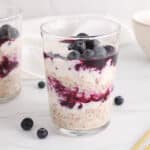 View on a jar of healthy berry cheesecake overnight oats layered with fruits.