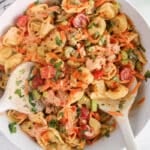 Vegan buffalo tortellini pasta salad with raw vegetables, fresh herbs and garnished with spices.