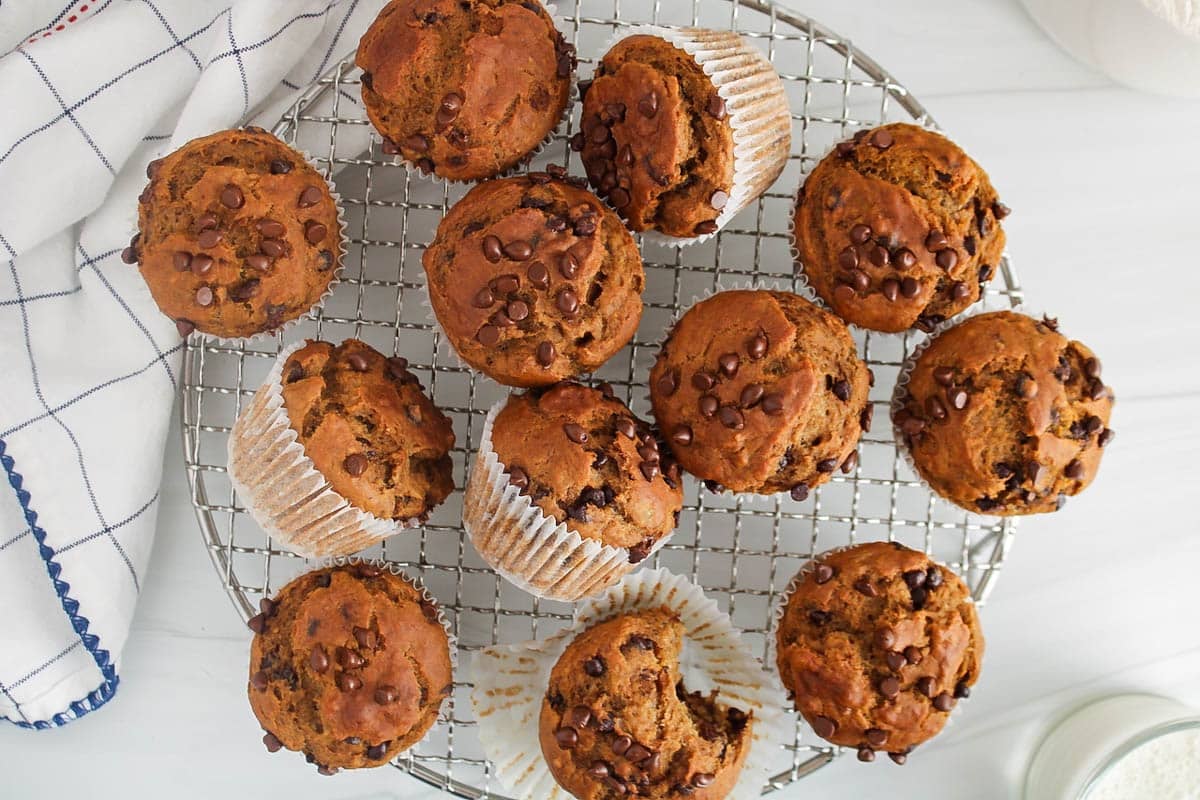 A batch of vegan healthy pumpkin banana muffins on a cooling rack.