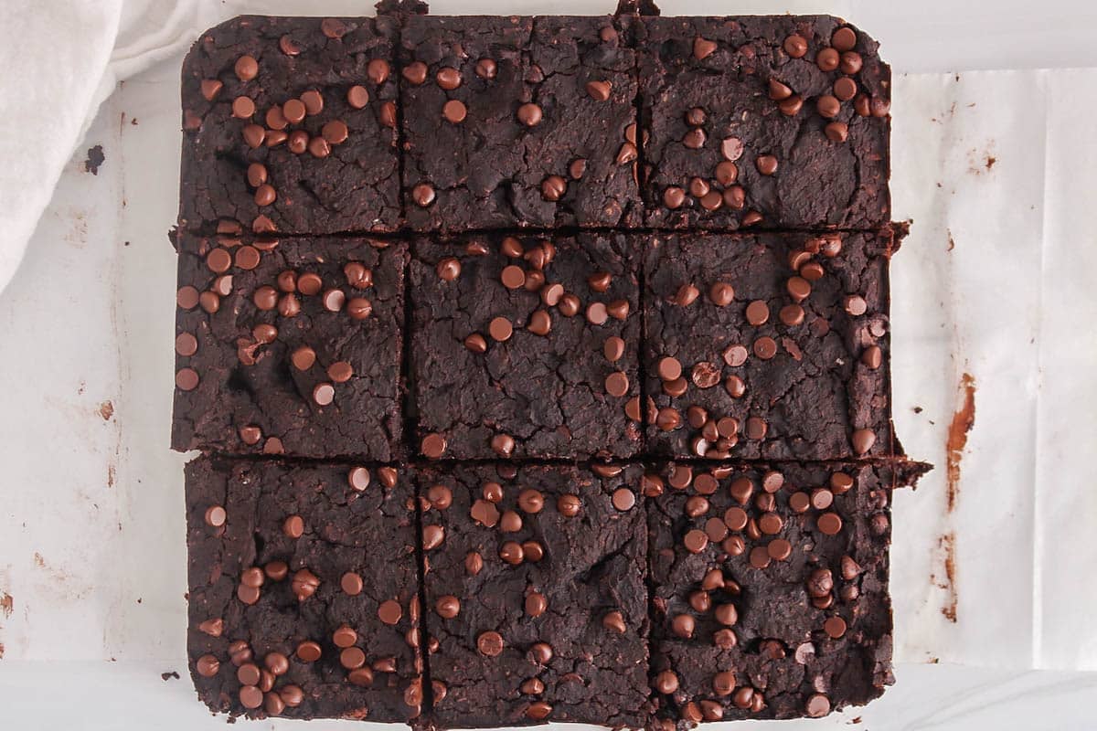 Vegan kidney bean brownies topped with chocolate chips and sliced in squares.