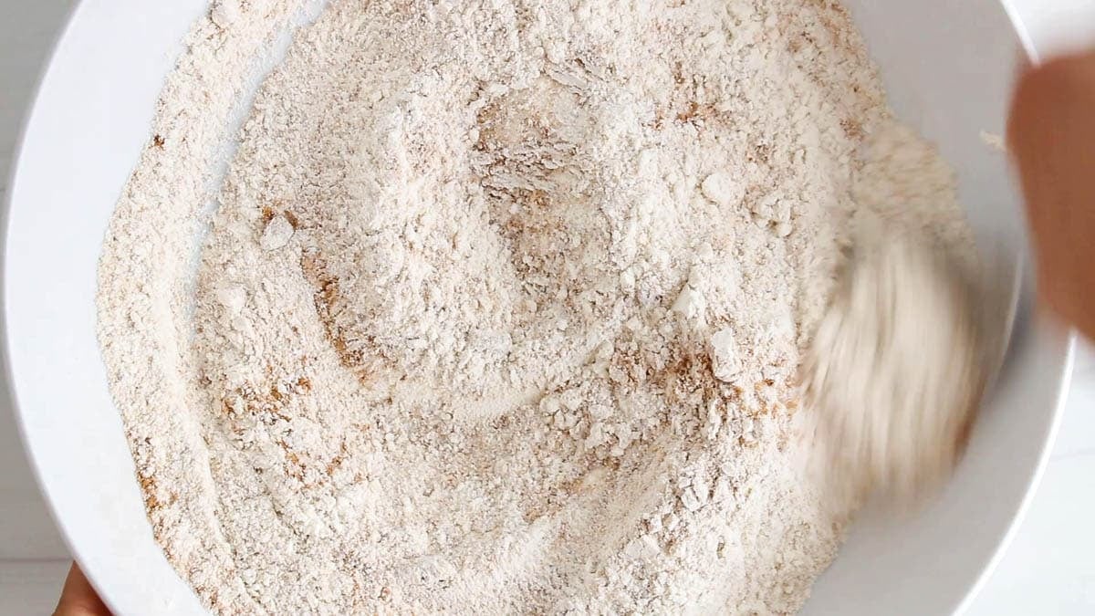 Dry ingredients to make apple cider donuts in a large white bowl.