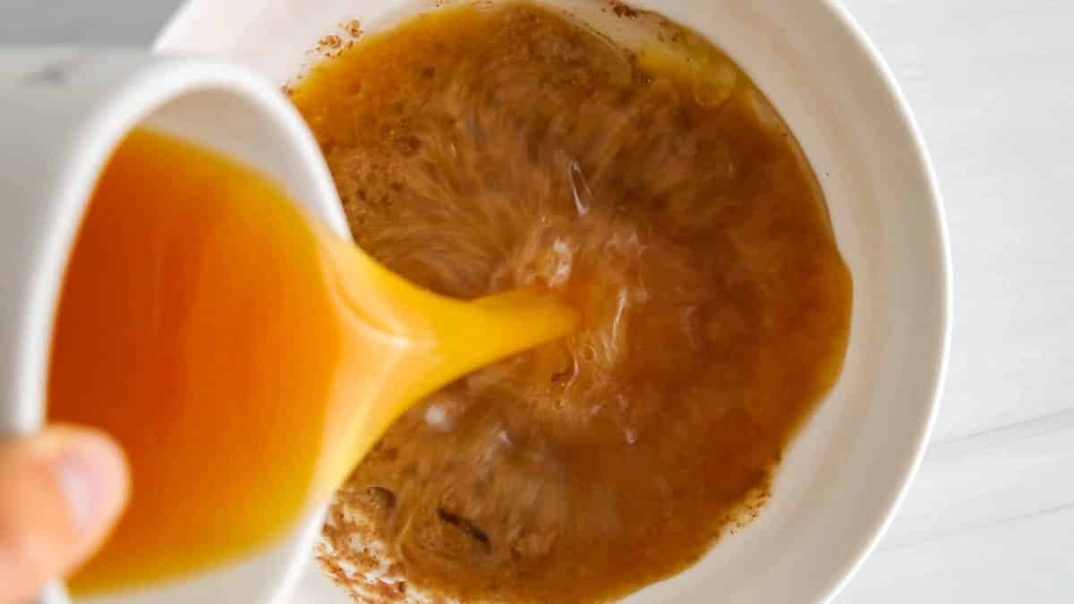 Pouring apple cider in a large white bowl with flax eggs and coconut oil.
