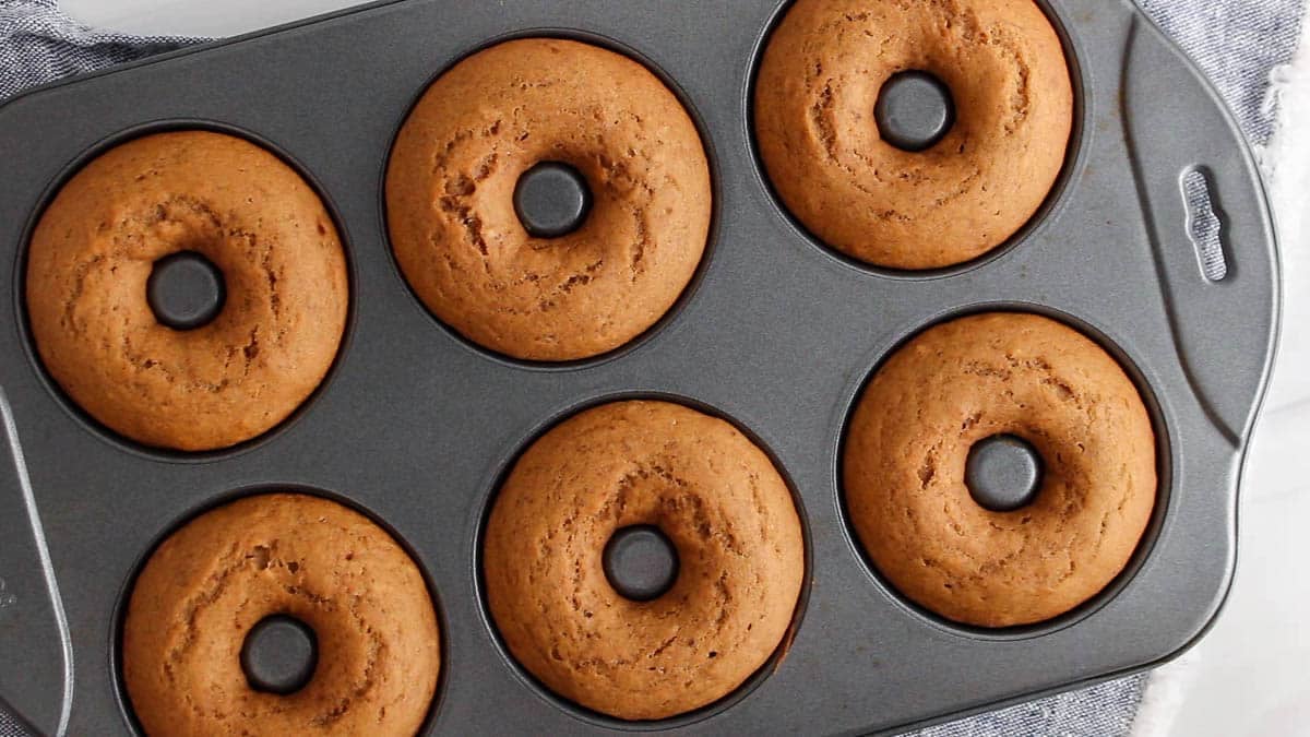 Baked apple cider donuts in a donut mold.