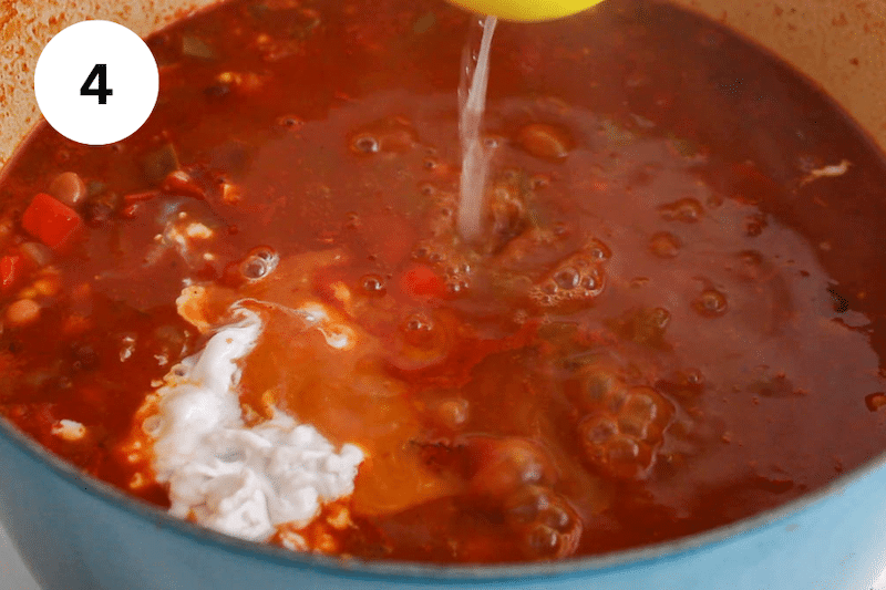 Lime juice squeezing into a large pot of soup.