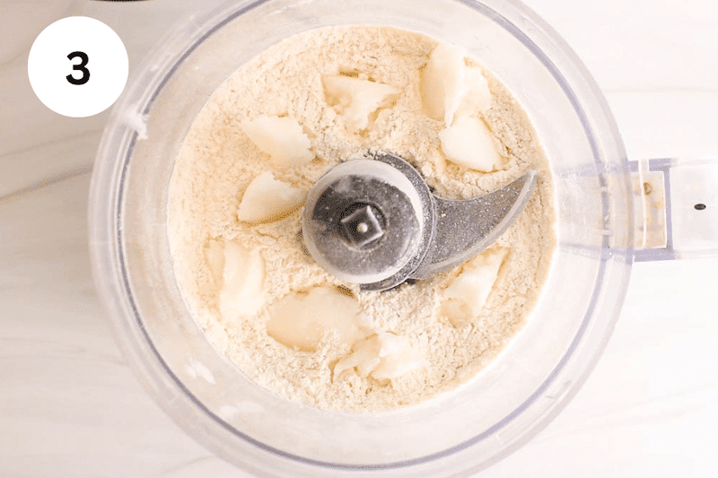 Flour mixture topped with coconut oil in a food processor.