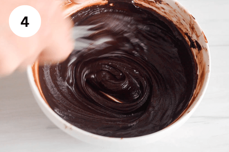Whisk stirring in a bowl with a thick chocolate sauce.