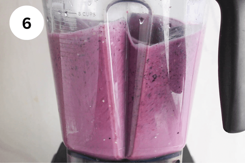 A bright purple mixture blending in a blender.