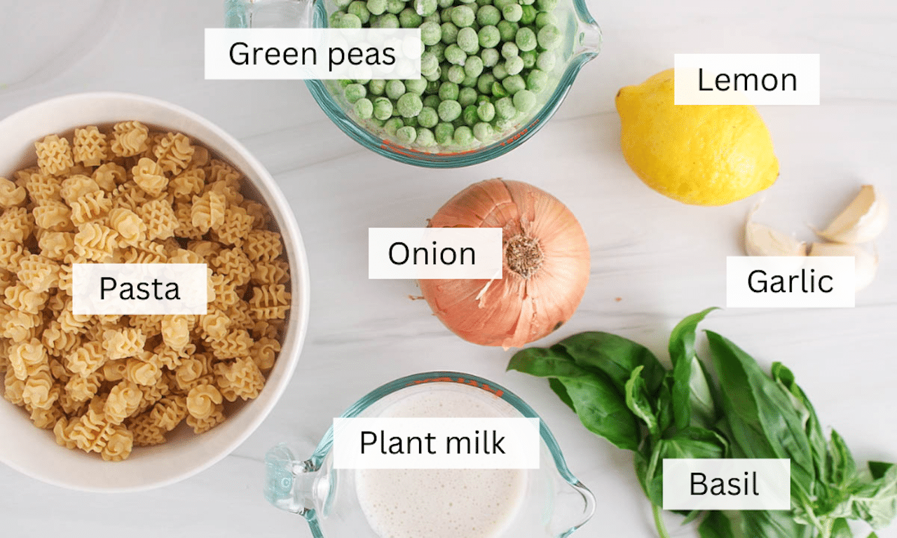 Ingredients to make a green pea pasta sauce over a white table.