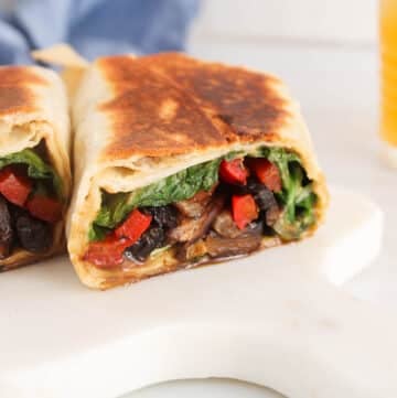 Vegan portobello mushroom wrap sliced in half and placed on a white board.
