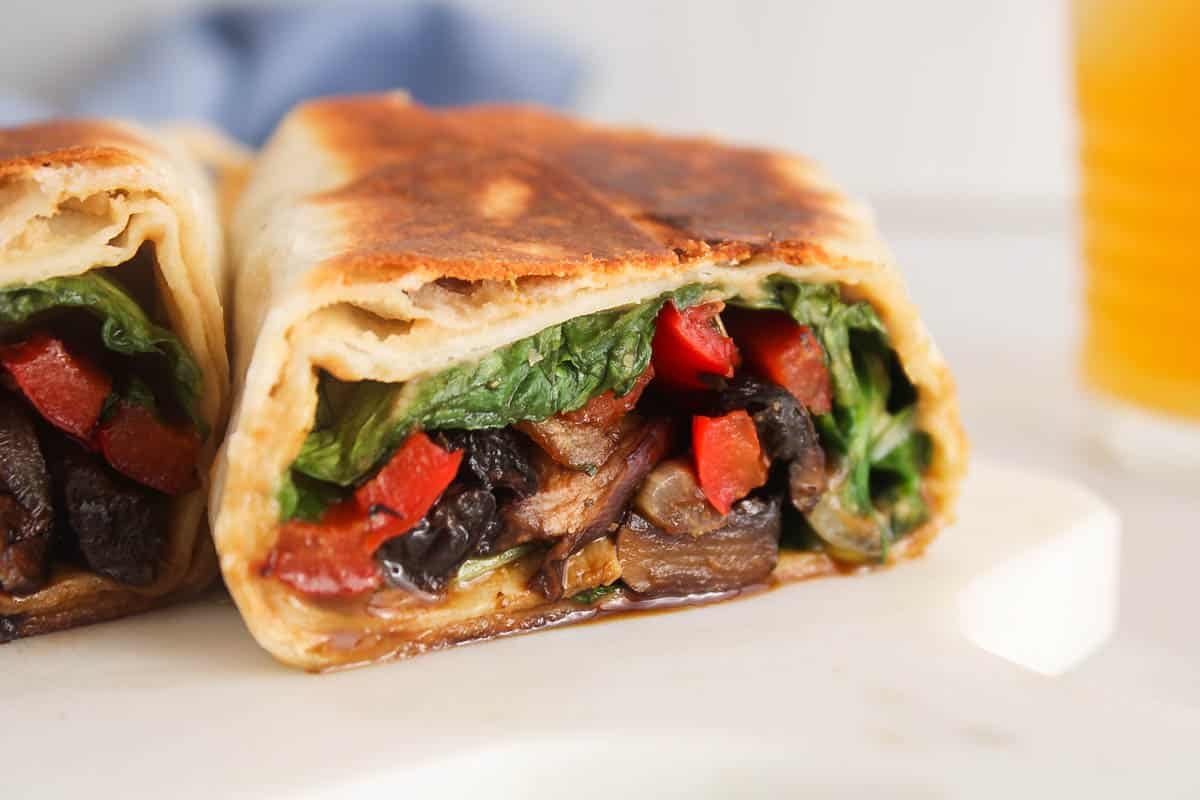 Showing the filling vegetables in a portobello wrap sliced in half.