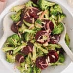 Large white bowl filled with a broccoli beet salad and 2 large serving spoons.