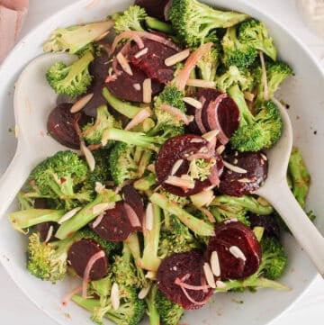 Large white bowl filled with a broccoli beet salad and 2 large serving spoons.