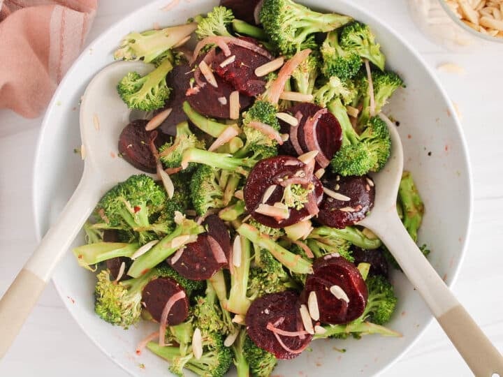 Large white bowl filled with a broccoli beet salad and 2 large serving spoons.