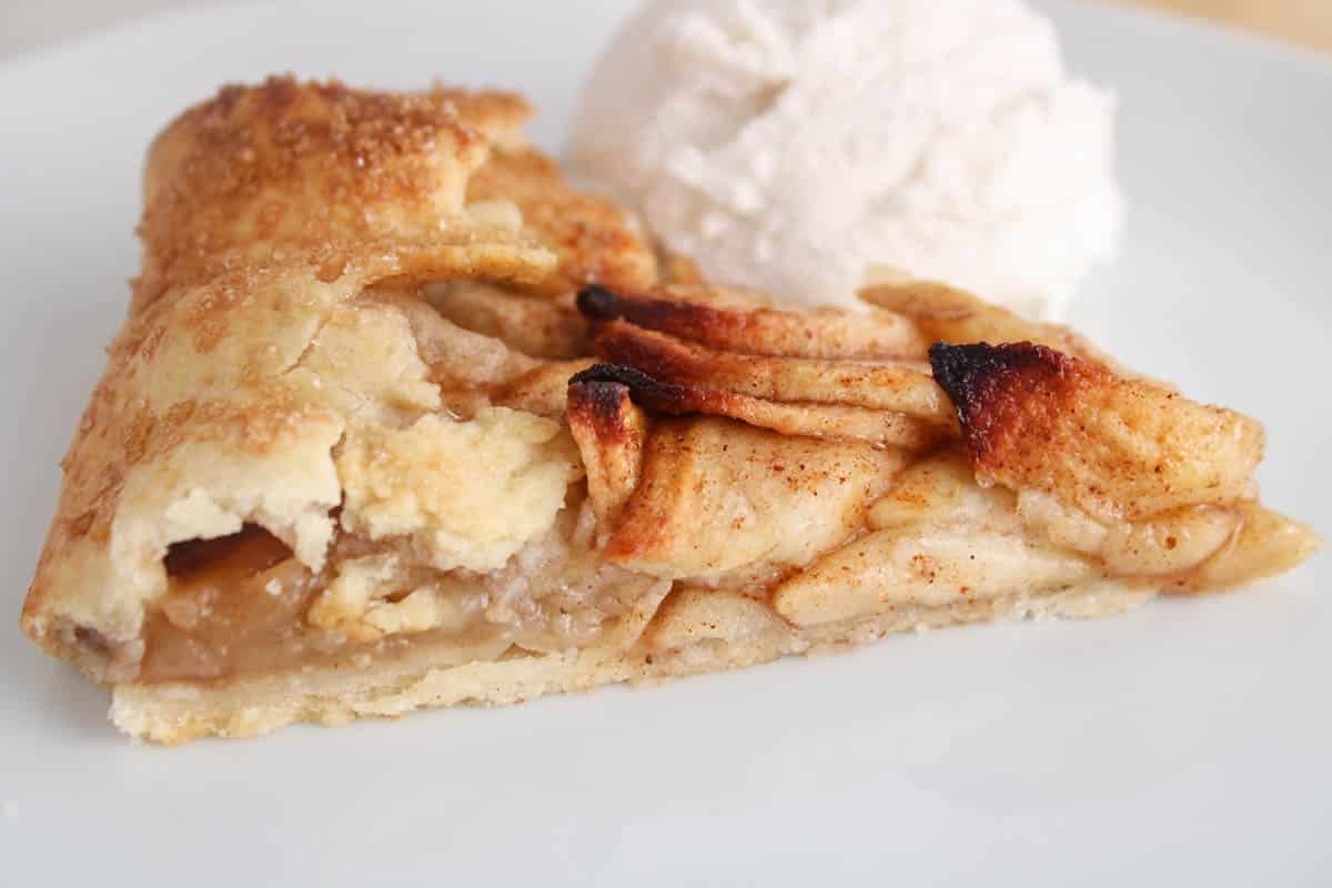 Vegan apple cinnamon galette slice on a plate with ice cream.