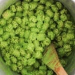 A large pot filled with short noodles tossed in a creamy pea pasta sauce.