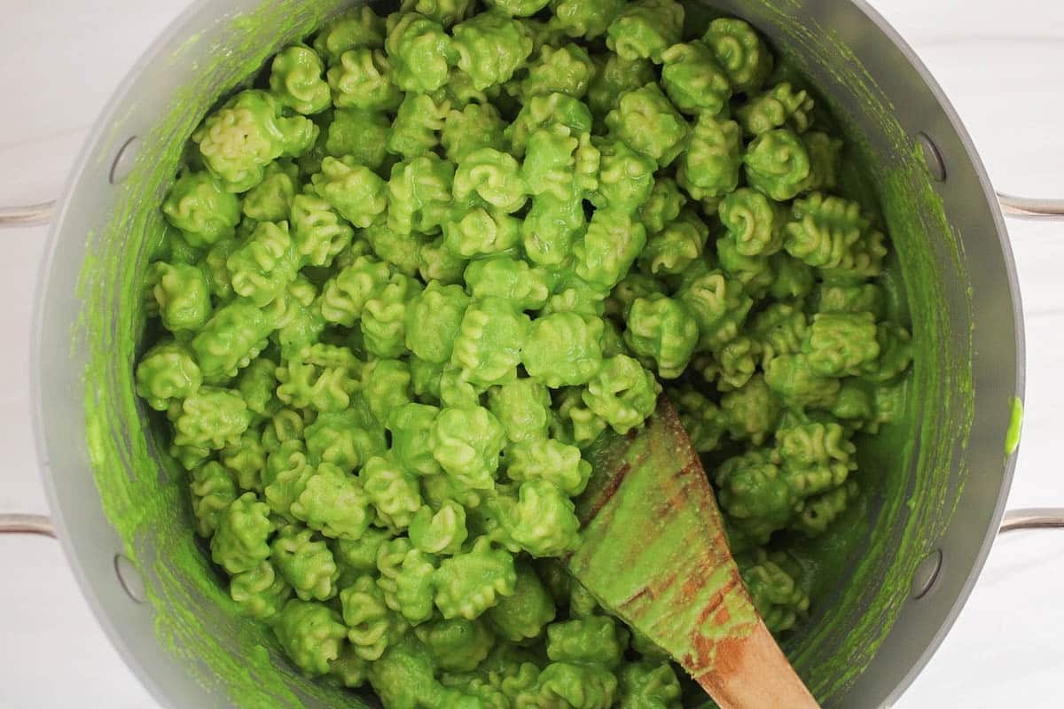 A large pot filled with short noodles tossed in a creamy pea pasta sauce.