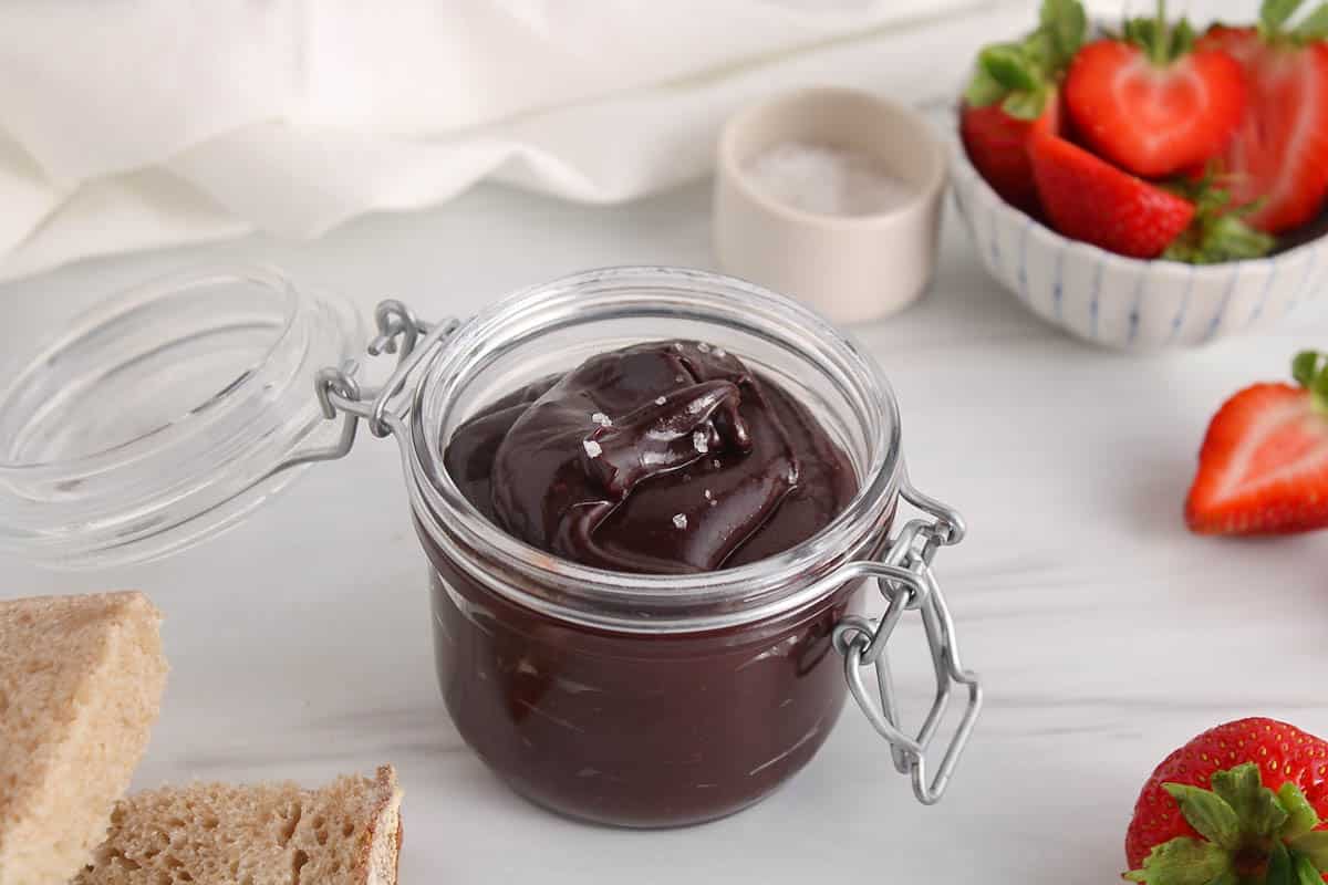A jar of dark chocolate tahini spread topped with sea salt.